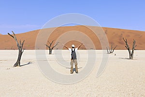 A young tourist with open arms at Deadvlei, Sossusvlei. Namibia, Africa