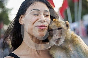 Young tourist petting a monkey in Jemaa el Fna square in Marrakech in Morocco