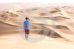 Young tourist in shorts hiking in giant dunes.