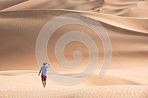 Young tourist in shorts hiking in giant dunes.