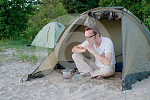 Young tourist waiting his dinner in camp on the gas burner