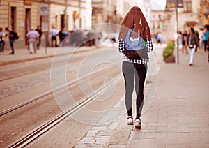 Young tourist woman with backpack walk by street in old europe city, summer fashion style