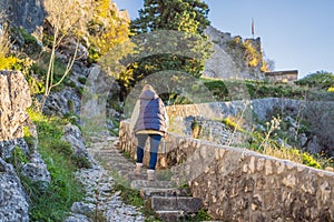 Young tourist woman enjoying a view of Kotor Bay, Montenegro. Kotor Old Town Ladder of Kotor Fortress Hiking Trail