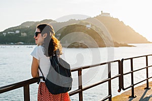 Young tourist woman enjoying the view of San Sebastian bay in Spain at sunset photo