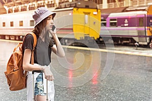 Young tourist woman holding cellphone and call Find accommodation on railway station. Travel concept