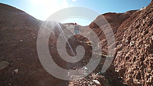 Young tourist woman in shorts with backpack descent from the red mountains and falls 50 fps