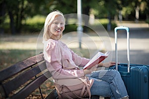 Young tourist woman sitting in the park with book