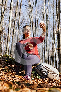 Young tourist woman take a picture in the autumn forest