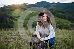 Young tourist woman traveller with backpack sitting in nature, resting.