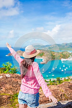 Young tourist woman with view of English Harbor from Shirley Heights, Antigua, paradise bay at tropical island in the