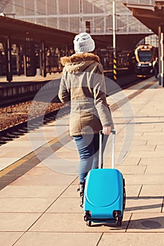 Young tourist woman walking, dragging luggage suitcase bag. Girl at railway station. Journey concept. Lifestyle, travelling, vacat