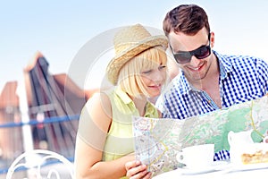 Young tourists with a map in a cafe