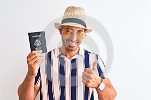 Young tourtist man wearing summer hat and holding USA passport over isolated background happy with big smile doing ok sign, thumb