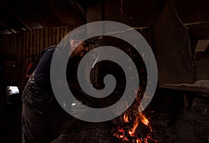 Young traditional Blacksmith working with open fire