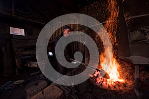 Young traditional Blacksmith working with open fire