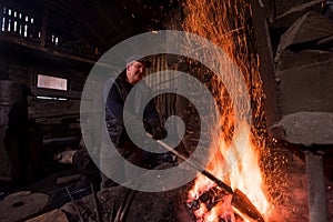 Young traditional Blacksmith working with open fire