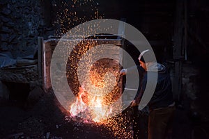 Young traditional Blacksmith working with open fire