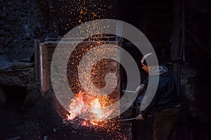 Young traditional Blacksmith working with open fire