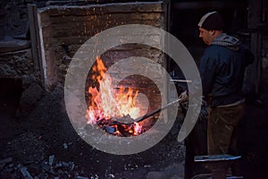 Young traditional Blacksmith working with open fire