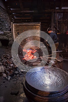 Young traditional Blacksmith working with open fire