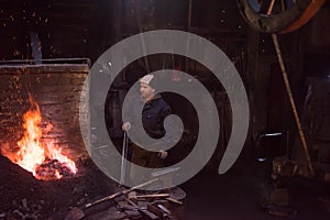 Young traditional Blacksmith working with open fire