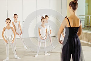 Young trainer coach of the ballet school helps young ballerinas