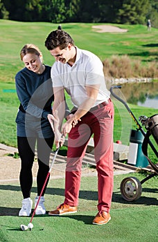 Young trainer showing player how to hit ball