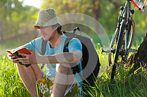 Young traveler with bicycle reading the book photo