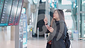 Young traveler female checking flight arrive and departure board