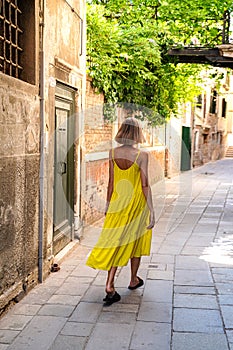 Young traveler girl on summer holidays in Europe walking on the old city street of Venice, Italy. Female back view