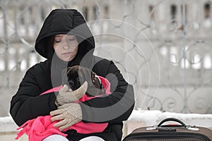 A young traveler girl is waiting for a train with her pet