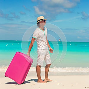 Young traveler with his luggage on a tropical beach