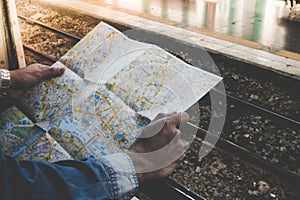 Young traveler holding travel map outside train window on a platform in the train station.