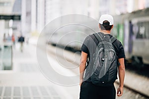 Young traveler man with backpack in the railway at train station. travel concept