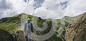 Young Traveler Man Standing On Top Of Cliff In Mountains And Enjoying View Of Nature, Rear View