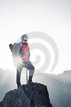 Young traveler in red snow jacket and a backpack standing on blue isolated background. Looking upwards in the sky with confidence