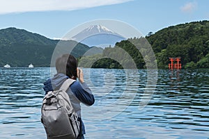 Young traveler takeing photo of  Hakone shrine with mt.Fuji at  lake Ashi