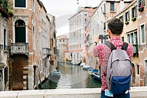 Young traveler taking a photo with his smartphone of a canal in Venice - Italy