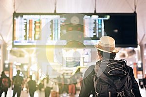 Young traveler or tourist looking at airport time board for flight schedule