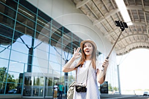 Young traveler tourist woman with retro vintage photo camera show OK sign doing selfie on mobile phone with monopod