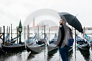Young traveler in Venice standing by the canal on a rainy day