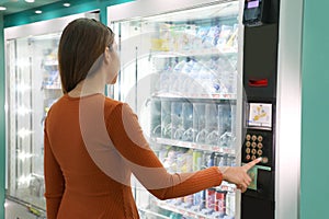 Young traveler woman choosing a snack or drink at vending machine in airport. Vending machine with girl