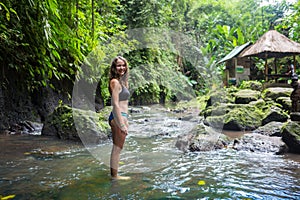 Young traveler woman in the jungle river. Rainforest of Bali island. Tourist adventure concept.