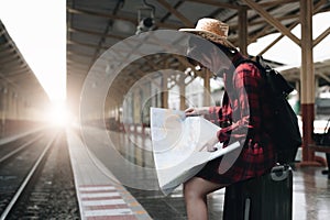 Young traveler woman looking on maps planning trip at train station. Summer and travel lifestyle concept