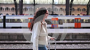 Young traveler woman with luggage walking at platform train station