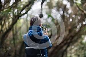 Young traveler woman taking a photo of forest landscape in Anaga Country Park photo