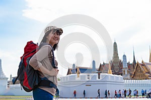 Young traveler women back packer, travelling alone in city scape in Thailand, Grand Palace as a blurred background