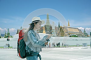 Young traveler women back packer, travelling alone in city scape in Thailand, Grand Palace as a blurred background