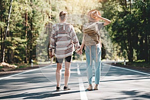 Young travelers hipsters couple holding hands and looking forward to a joint journey