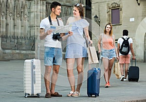 young travelers holding map in hands and looking for their way in european town